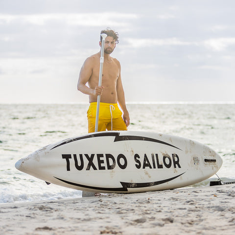 A man was standing with paddle in his hand, behind the Tuxedo Sailor inflatable SUP